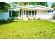 Charming single-story home with well-manicured lawn and inviting front porch seating area at 135 Emerald Ln, Largo, FL 33771