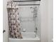 Clean white tiled bathtub and shower combination with floral patterned shower curtain at 15420 Aubrey Ave, Spring Hill, FL 34610