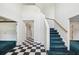 Grand foyer featuring high ceilings, black and white checkered flooring and staircase with blue carpeting at 15420 Aubrey Ave, Spring Hill, FL 34610