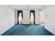 Spacious living room featuring blue carpet, decorative curtains and access to foyer at 15420 Aubrey Ave, Spring Hill, FL 34610