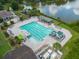 Aerial view of a community pool, featuring a water slide, lounge area, and lush landscaping by a lake at 17734 Long Ridge Rd, Tampa, FL 33647