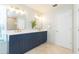 Bathroom featuring double sinks, blue vanity, quartz countertops, tile flooring, and modern lighting at 17734 Long Ridge Rd, Tampa, FL 33647