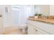 Well-lit bathroom featuring a granite countertop, white cabinets, tub with tile surround, and tiled floors at 17734 Long Ridge Rd, Tampa, FL 33647