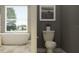 Bathroom with standalone tub beside a toilet and gray walls, illuminated by a bright window view at 18469 Serene Lake Loop, Lutz, FL 33548