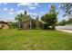 Charming green home featuring a stone chimney, lush landscaping, and a well-maintained lawn at 18914 Geraci Rd, Lutz, FL 33548