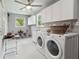 Bright laundry room with modern washer and dryer, sink, cabinets, and tiled accent wall at 18914 Geraci Rd, Lutz, FL 33548
