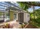 Backyard with a screened-in porch, adjacent shed, and paver patio area surrounded by landscaping at 18914 Geraci Rd, Lutz, FL 33548