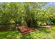 Tranquil waterfront view featuring a wooden deck and a kayak by a grassy bank at 18914 Geraci Rd, Lutz, FL 33548