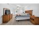 Well-lit bedroom with wood dresser, nightstand, ceiling fan and warm-toned wood-look floors at 205 Wimbly Pl, Sun City Center, FL 33573