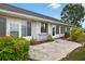 Charming home exterior featuring a concrete patio, lush landscaping, and light gray paint at 205 Wimbly Pl, Sun City Center, FL 33573