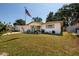 Single-story home featuring a manicured lawn, mature trees, and an American flag at 2135 Pocahontas Dr, Largo, FL 33774