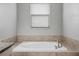 A soaking tub is surrounded by neutral tile and located underneath a window at 21395 Southern Charm Dr, Land O Lakes, FL 34637