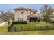 Spacious backyard featuring a black metal fence, lush green grass, and a covered patio at 2388 Oakwood Preserve Dr, Wesley Chapel, FL 33543
