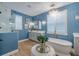An elegant blue bathroom showcases a soaking tub, crystal chandelier and gray vanity at 2388 Oakwood Preserve Dr, Wesley Chapel, FL 33543
