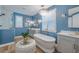 An elegant blue bathroom showcases a soaking tub, crystal chandelier and gray vanity at 2388 Oakwood Preserve Dr, Wesley Chapel, FL 33543