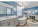 A modern blue bathroom features a soaking tub, double vanity, and decorative light fixtures at 2388 Oakwood Preserve Dr, Wesley Chapel, FL 33543