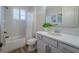 Bright bathroom features a shower-tub combo, gray vanity with white countertop, modern fixtures, and decorative art at 2388 Oakwood Preserve Dr, Wesley Chapel, FL 33543