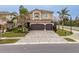 Two-story home featuring a three-car garage, paver driveway, neutral stucco, and manicured landscaping at 2388 Oakwood Preserve Dr, Wesley Chapel, FL 33543