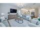 Open concept living room with gray sofa, chairs, TV and kitchen in the background at 2388 Oakwood Preserve Dr, Wesley Chapel, FL 33543