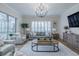 Elegant living room with shutters, gray sofa, chairs and a modern chandelier at 2388 Oakwood Preserve Dr, Wesley Chapel, FL 33543