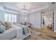 Bright primary bedroom with tray ceiling, modern chandelier, and plantation shutters at 2388 Oakwood Preserve Dr, Wesley Chapel, FL 33543