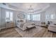 Bright primary bedroom with tray ceiling, modern chandelier, and plantation shutters at 2388 Oakwood Preserve Dr, Wesley Chapel, FL 33543