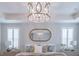 A beautiful main bedroom features a decorative chandelier and a large mirror over the bed at 2388 Oakwood Preserve Dr, Wesley Chapel, FL 33543