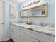 Bathroom featuring a dual sink vanity with white cabinets, marble countertop and framed mirror at 2400 Winding Creek Blvd # 4-101, Clearwater, FL 33761