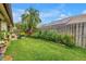 Lush backyard with green lawn, garden beds, mature palms, and solar panels on the roof at 2475 Bay Berry Dr, Clearwater, FL 33763