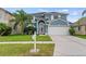 Charming two-story blue home featuring a well-manicured lawn, two-car garage and elegant entryway at 25521 Bruford Blvd, Land O Lakes, FL 34639