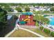 Aerial view of a well-maintained playground features a covered play area, slide, and a white picket fence surround at 25521 Bruford Blvd, Land O Lakes, FL 34639
