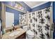 This bathroom features blue walls, a sink with granite countertop, a toilet, and a shower with a black and white shower curtain at 2814 Duncan Tree Cir, Valrico, FL 33594