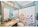 This bathroom features blue walls, a sink with granite countertop, a toilet, and a shower with a flower shower curtain at 2814 Duncan Tree Cir, Valrico, FL 33594