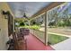 A spacious front porch boasts a red floor, ceiling fan, and a relaxing seating area to enjoy the lush green views at 3018 Pemberton Trace Ct, Plant City, FL 33565