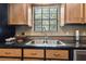 Close-up of a kitchen sink area featuring a stainless steel sink, wooden cabinets, and mosaic tile backsplash at 3018 Pemberton Trace Ct, Plant City, FL 33565
