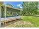 View of enclosed porch and grassy backyard with a large tree casting shade at 3203 21St Se Ave, Ruskin, FL 33570