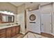 Bright bathroom with a wooden vanity, granite countertop, decorative mirror, and unique clock at 3212 E Merrin Rd, Plant City, FL 33567