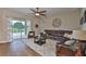 Cozy living room featuring a large leather sectional, wood-look tile, and sliding glass doors to a screened pool at 3212 E Merrin Rd, Plant City, FL 33567