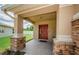 Close-up of the covered porch with brick-paved flooring and a red front door at 3305 Hoylake Ct, Land O Lakes, FL 34638