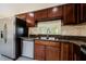 A kitchen features stainless steel appliances, including a refrigerator and dishwasher, with dark wood cabinets and granite countertops at 3305 Hoylake Ct, Land O Lakes, FL 34638