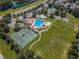 Aerial view of the community pool with a splash pad, tennis courts, basketball court, and manicured green space at 3305 Hoylake Ct, Land O Lakes, FL 34638