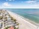 Panoramic view of beachside homes along a sandy shore meeting a calm, blue ocean at 352 La Hacienda Dr, Indian Rocks Beach, FL 33785