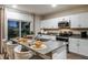 Bright kitchen with white cabinets, stainless steel appliances, island with seating, and sliding glass doors at 37206 Sagemoor Dr, Zephyrhills, FL 33541