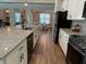 Open concept kitchen with granite counters, white cabinets, stainless appliances, and wood-look tile floors at 3895 Tate Ct, North Port, FL 34288