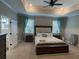 Serene main bedroom with tray ceiling, soft carpeting, and ample natural light from large windows at 3895 Tate Ct, North Port, FL 34288