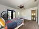 Cozy bedroom features french doors to a balcony, plush carpeting, and a large ceiling fan at 4313 W Vasconia St, Tampa, FL 33629