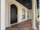 Welcoming entryway with a dark wood door, red brick tile, and arched windows at 4313 W Vasconia St, Tampa, FL 33629