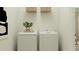 Functional laundry room featuring a modern white washer and dryer with a decorative plant at 4752 Southern Valley Loop, Brooksville, FL 34601