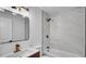 Updated bathroom with a white marbled tile surround, contrasting black fixtures, and modern vanity with gold faucet at 603 Amana Ave, Brandon, FL 33510