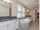 Spa-like bathroom with double sinks, a soaking tub, and elegant fixtures with a walk-in closet nearby at 6109 Marsh Trail Dr, Odessa, FL 33556